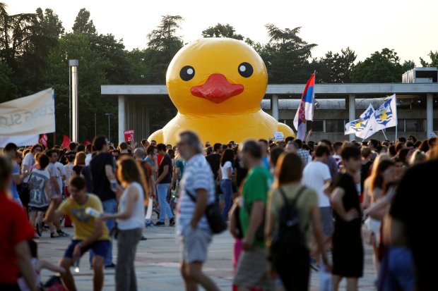 Protesters with flags walk past a rubber duck during protest against Belgrade Waterfront project